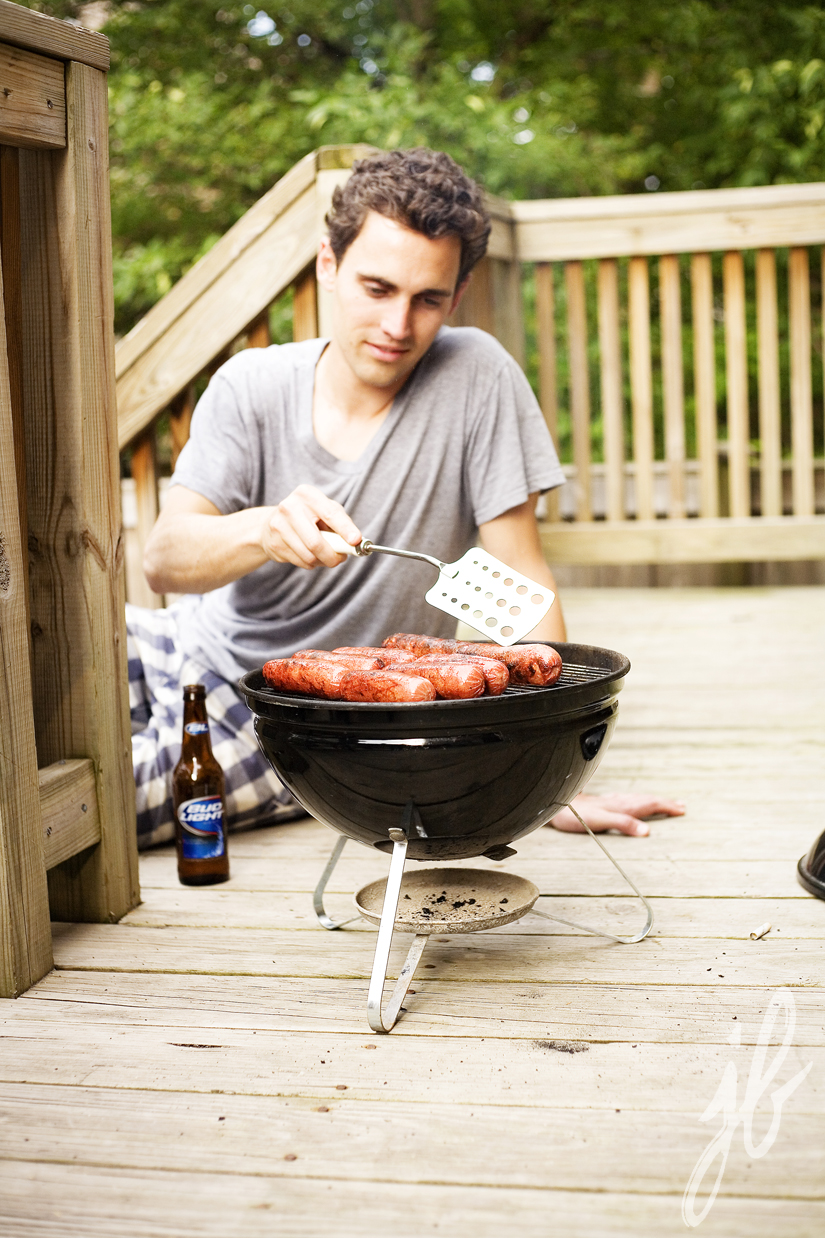 man grilling sausages on small charcoal grill