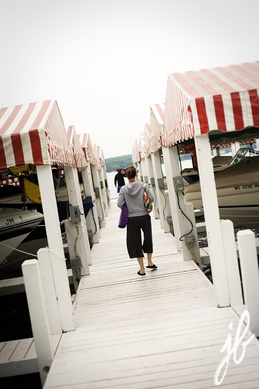 couple walks down lake geneva boat deck with red and white awnings 