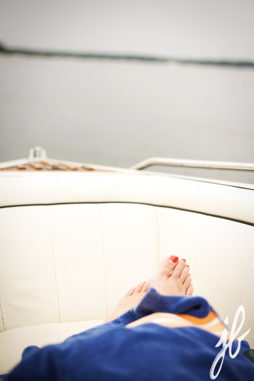 woman toes and beach towel at the front of a speed boat on lake geneva